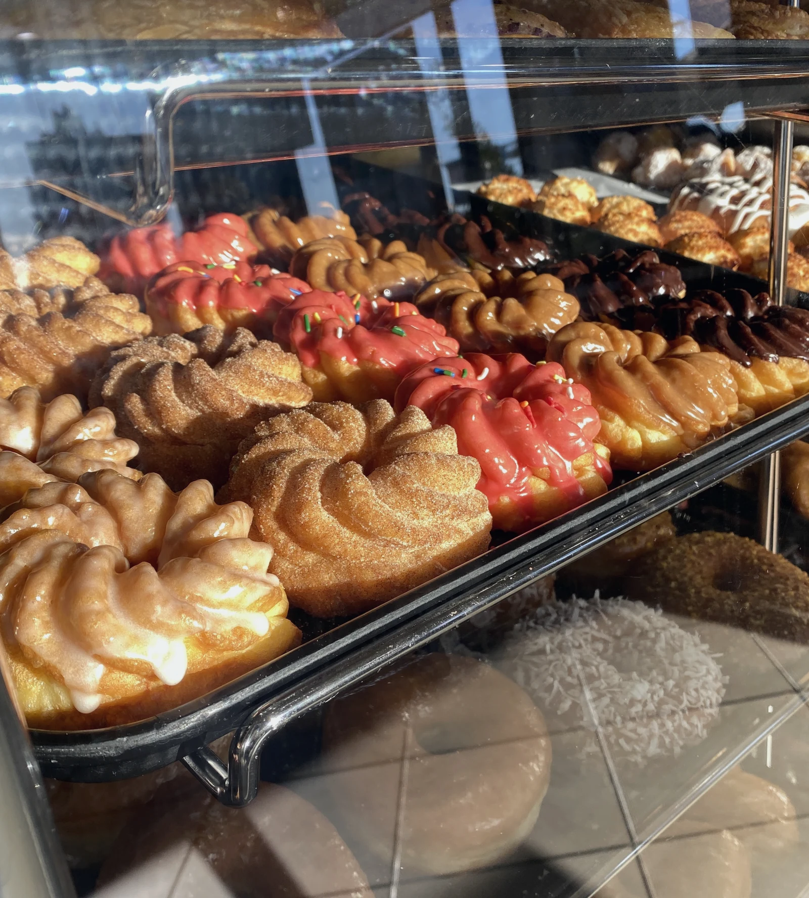 Dallas donut shop display case Donut shop display case stacked with crullers and glazed donuts